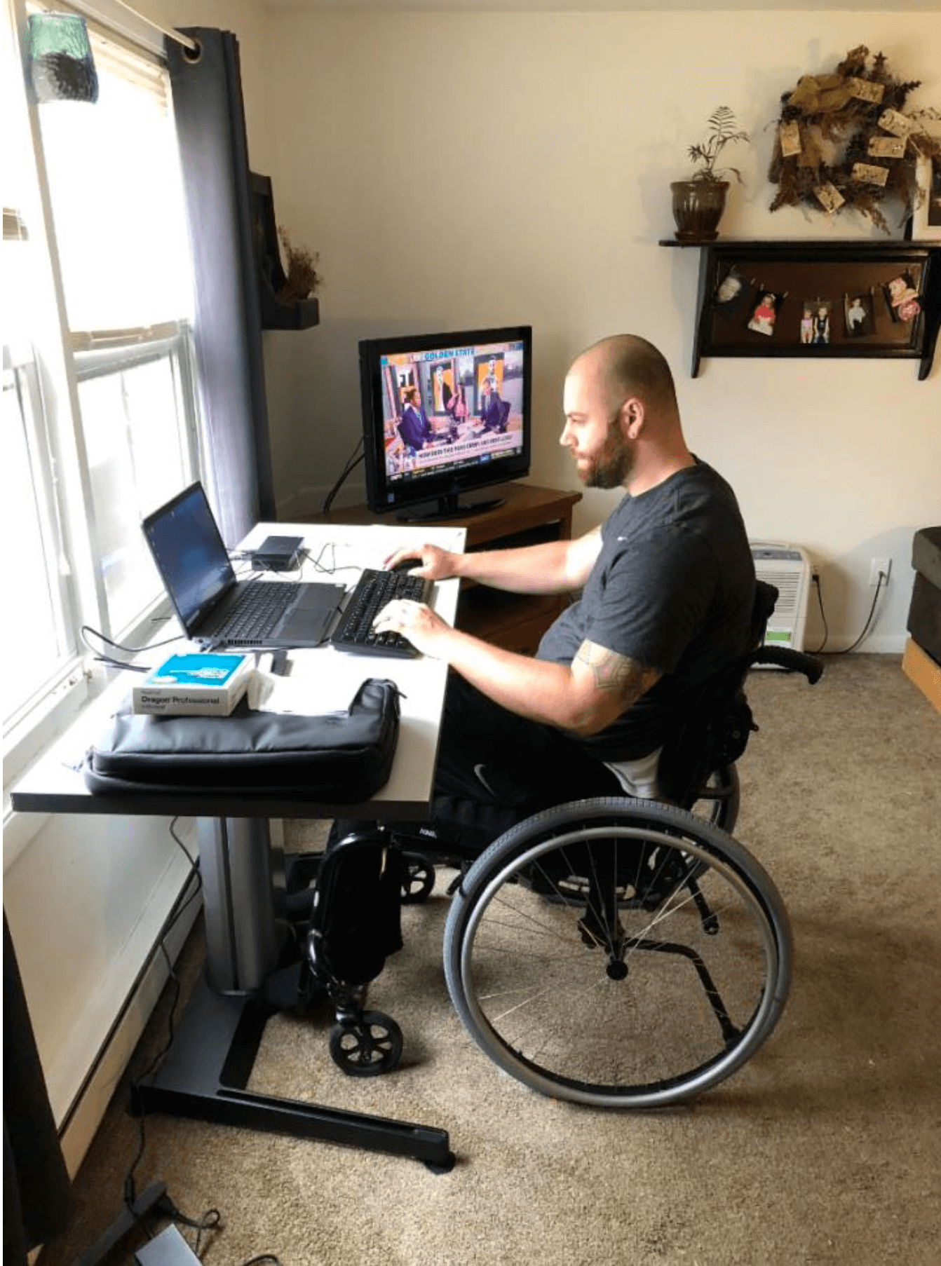 Man in a wheelchair sitting at a desk with a laptop