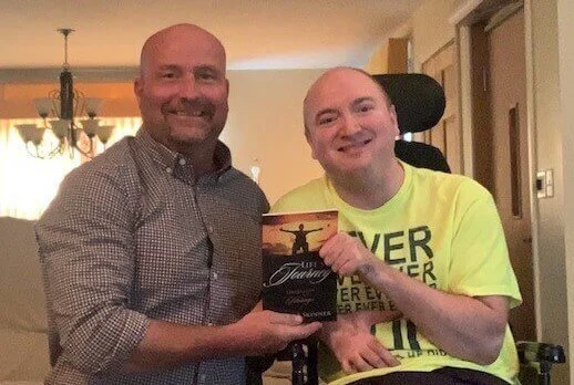 Picture of Mark McCabe on the left and Colten Skinner on the right holding Colten's book, Life's A Journey: Hardships to Blessings.