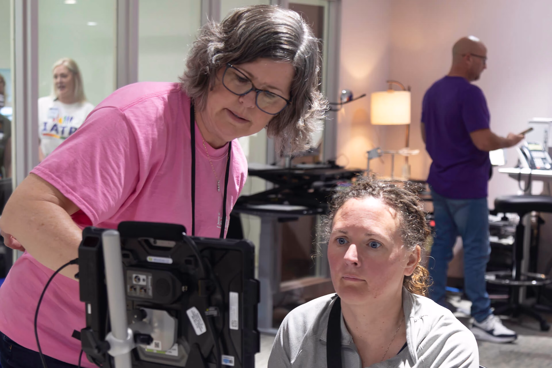 IATP Speech-Language Pathologist demonstrates an assistive technology device to a visitor.