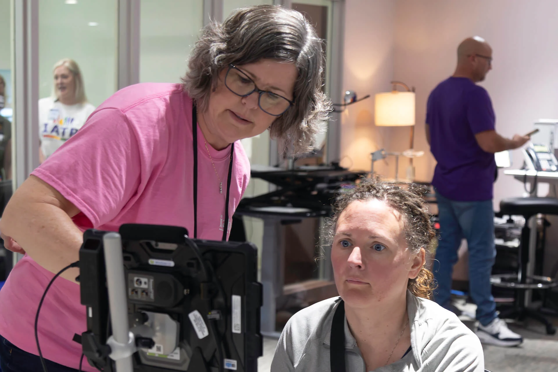 IATP Speech-Language Pathologist demonstrates an assistive technology device to a visitor.