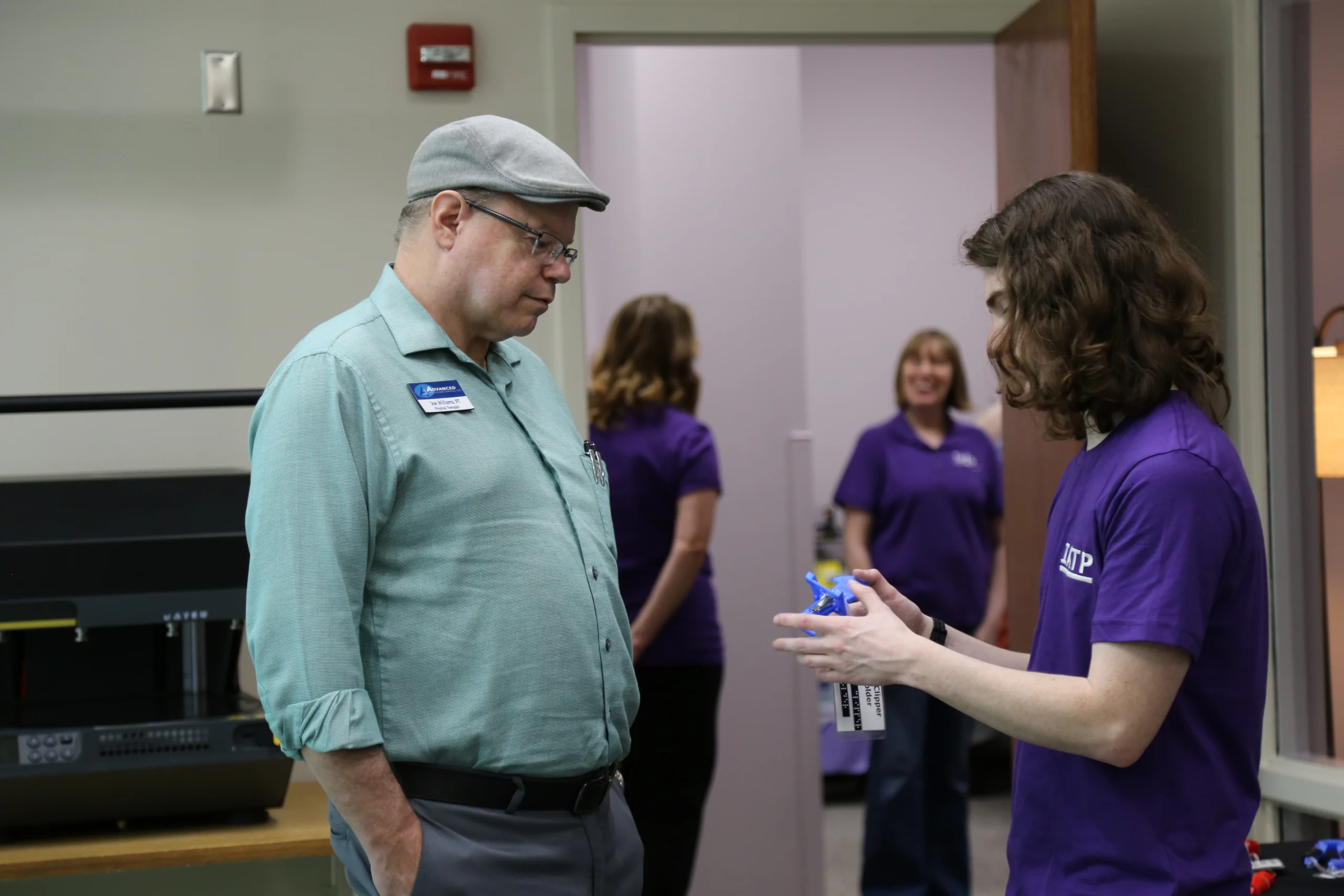 IATP staff member showing visitor a piece of assistive technology created in the IATP Makers Lab.