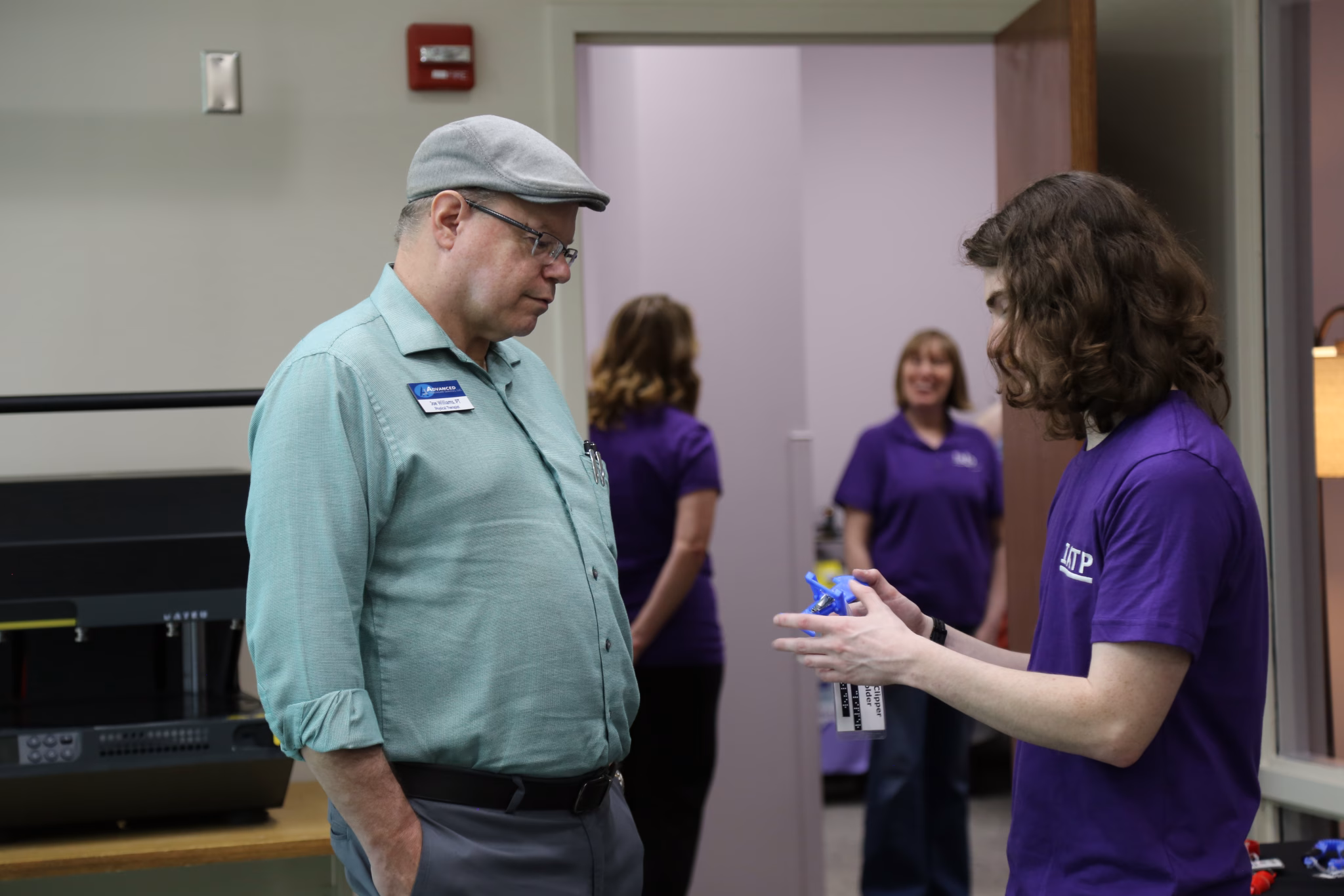 IATP staff member showing visitor a piece of assistive technology created in the IATP Makers Lab.
