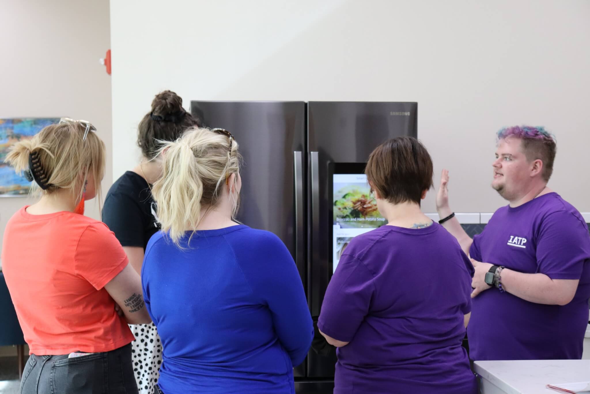 IATP staff member explaining the smart home technology refrigerator to a group of visitors.