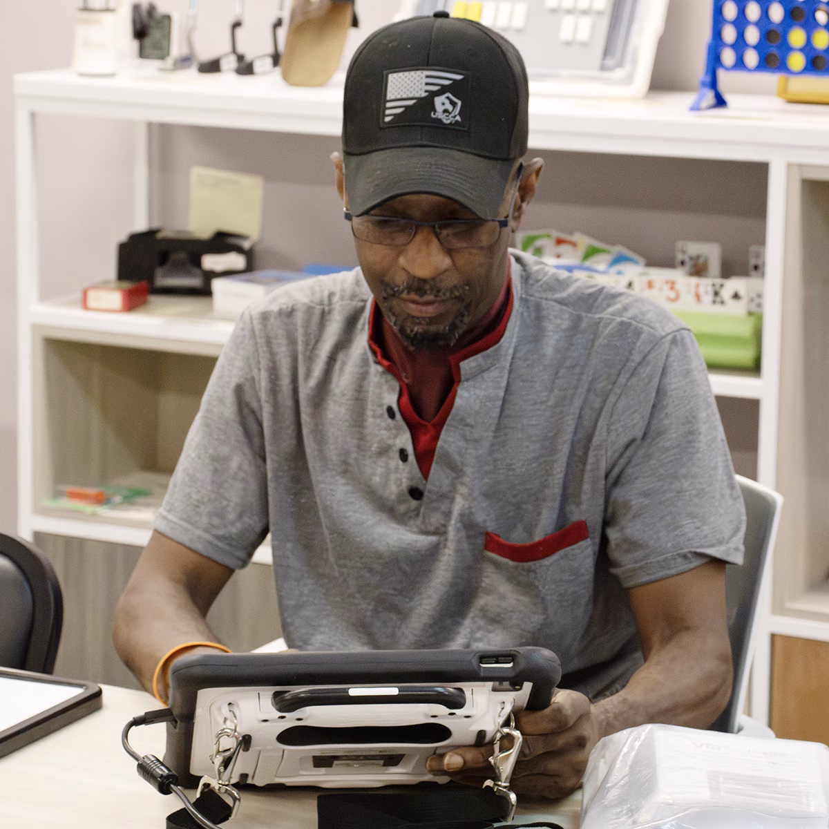A person holding a AAC device looking down at the device, focused on the screen A person holding a AAC device looking down at the device, focused on the screen