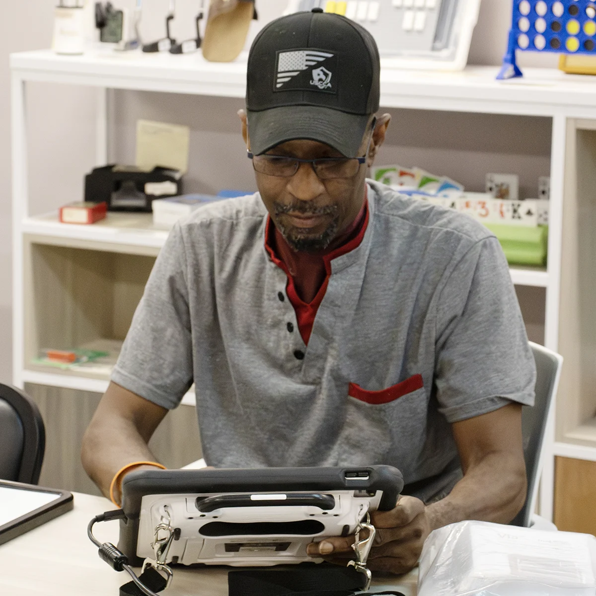 A person holding a AAC device looking down at the device, focused on the screen