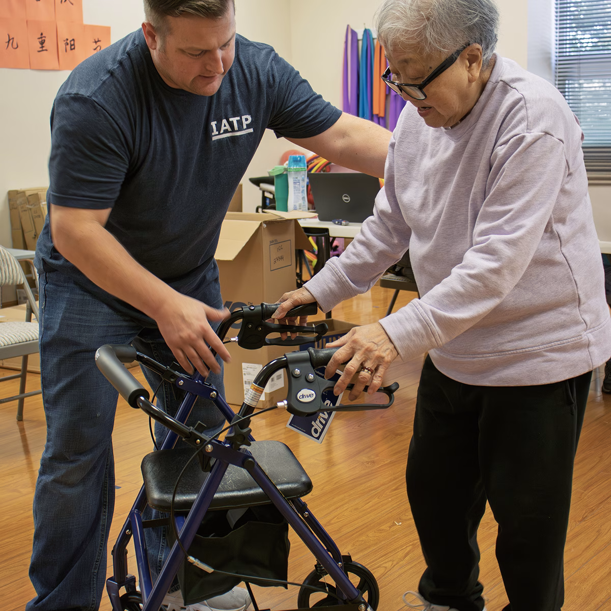 An IATP employee helps an older woman using a walker An IATP employee helps an older woman using a walker