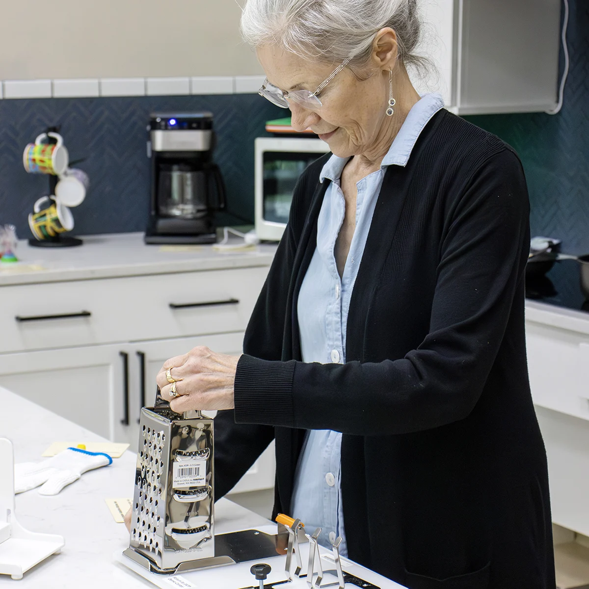 An older adult using an Assistive Technology grater in a kitchen