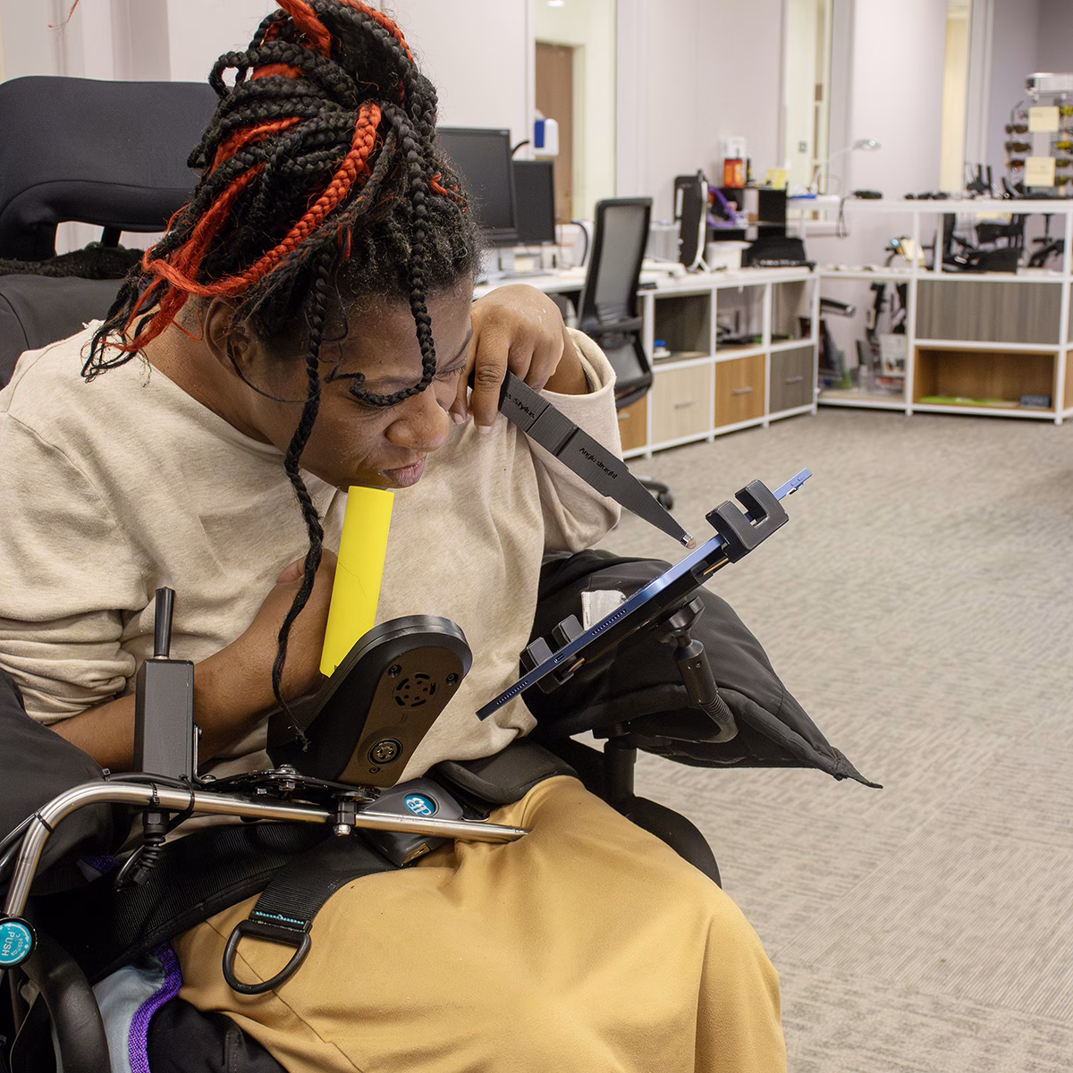 Person in a wheelchair using assistive technology with a tablet in an office setting Person in a wheelchair using assistive technology with a tablet in an office setting