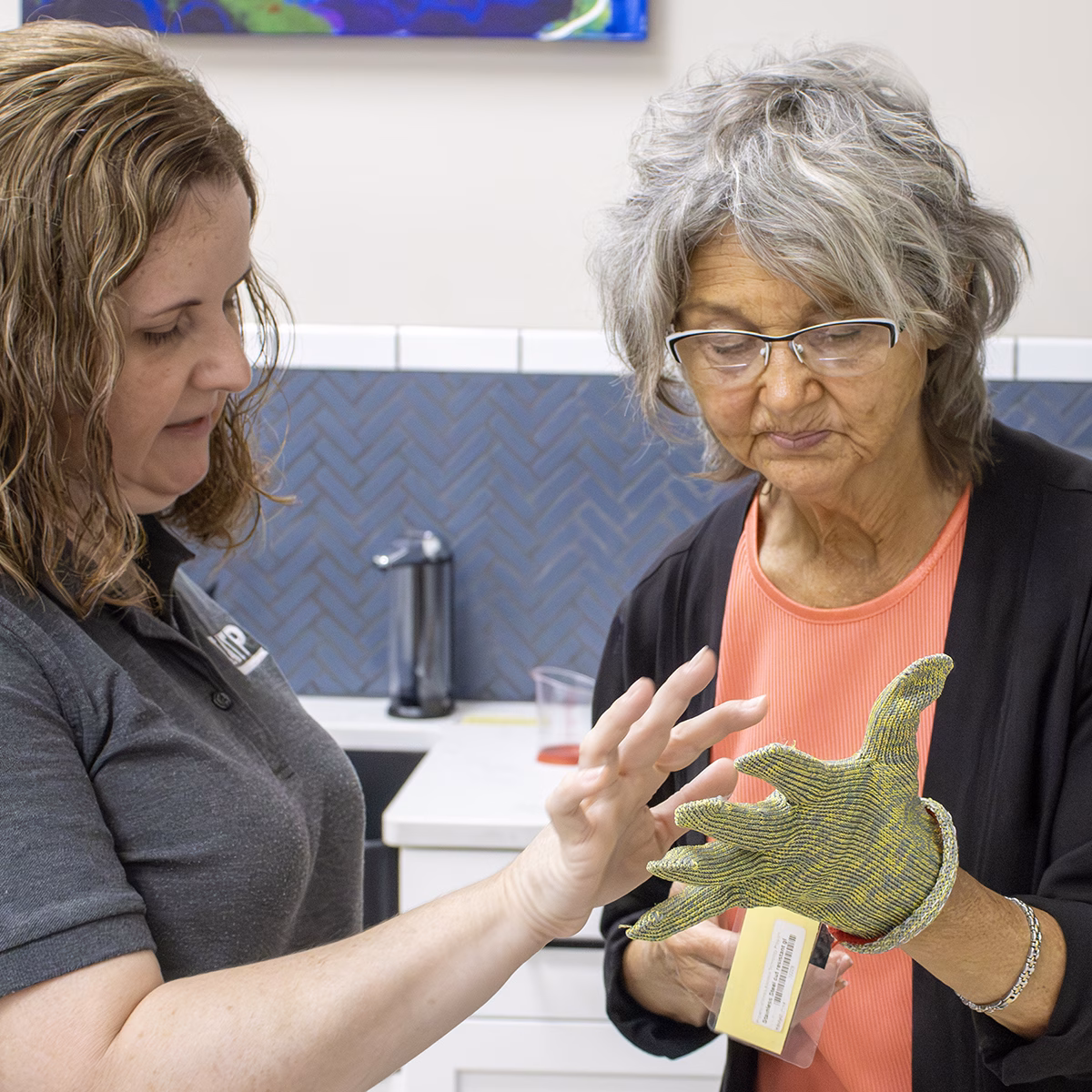 Two women examining a textured glove in a kitchen Two women examining a textured glove in a kitchen