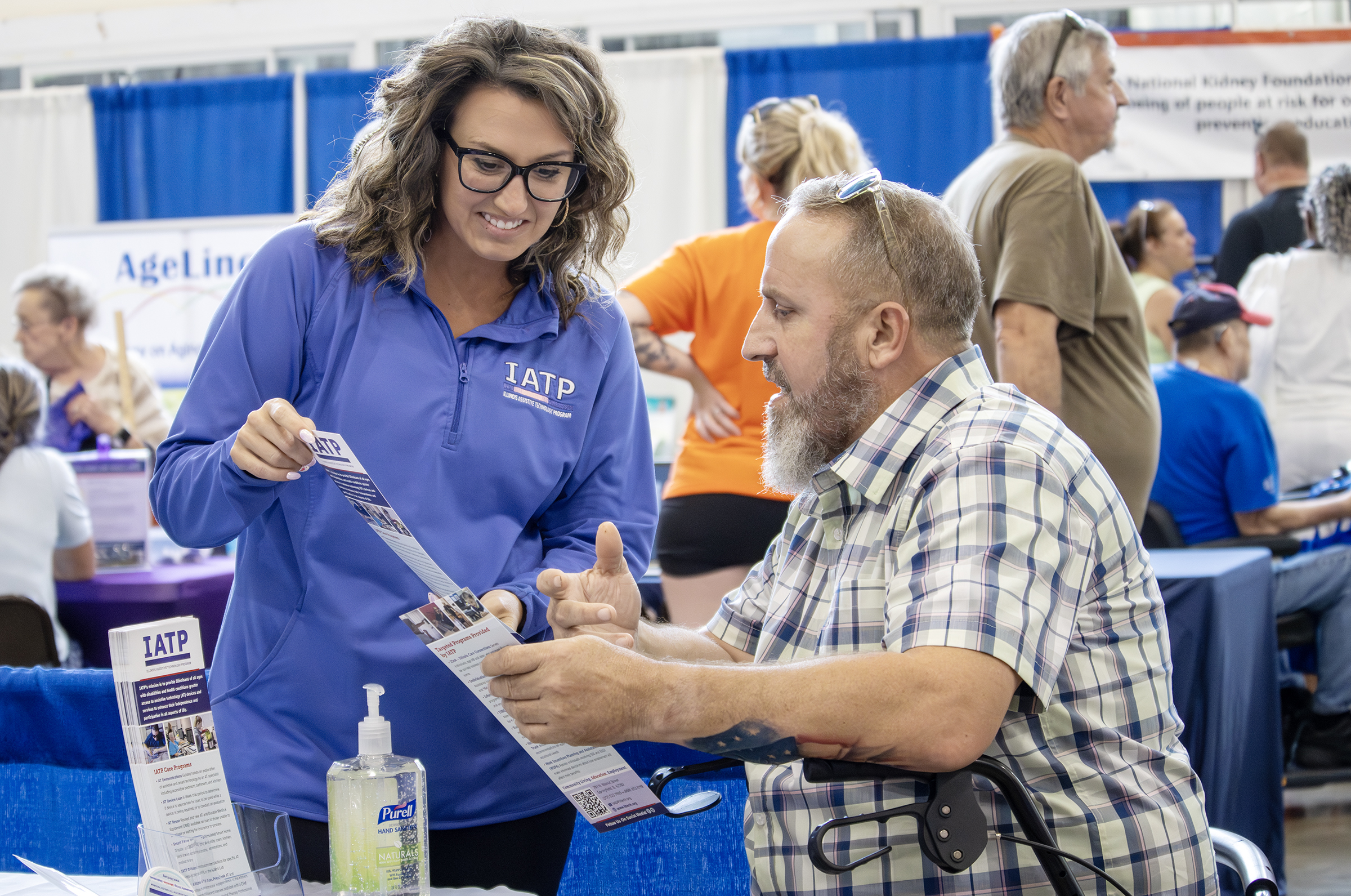 image An IATP employee discusses a brochure with a seated man at the state fair.