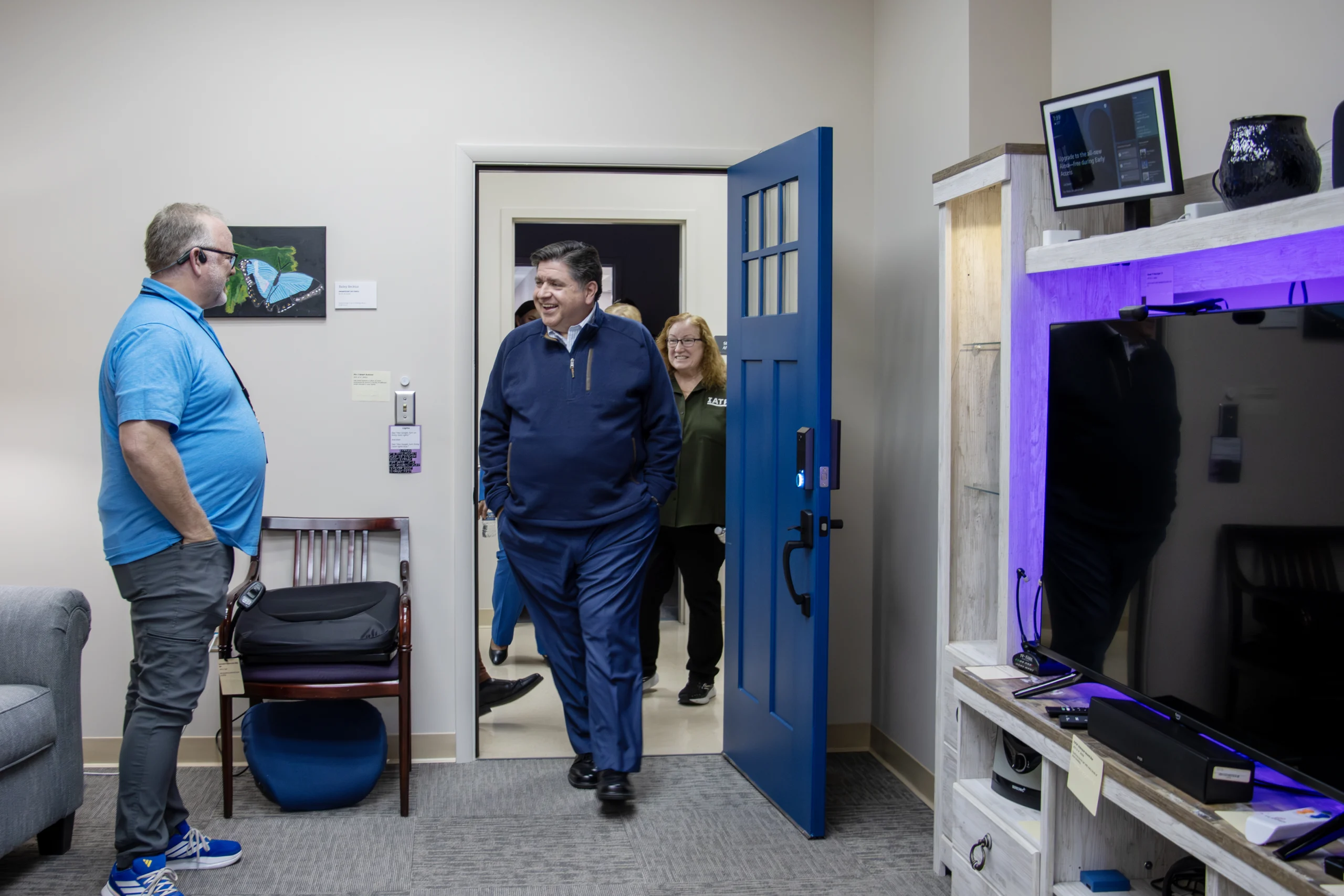 Governor Pritzker walking in the front door of the IATP smart Home. An IAT staff member is standing waiting to greet him.