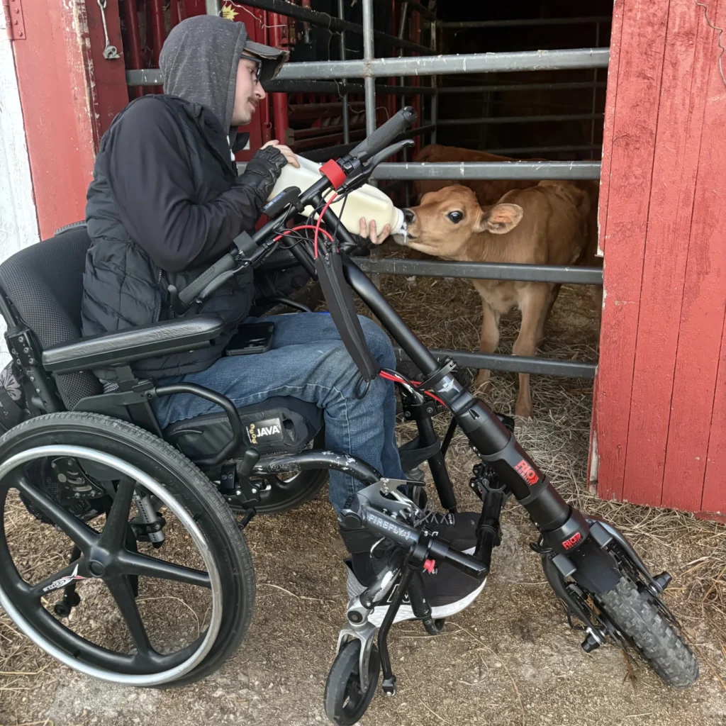 Jared sitting in in the Firefly feeding a baby calf