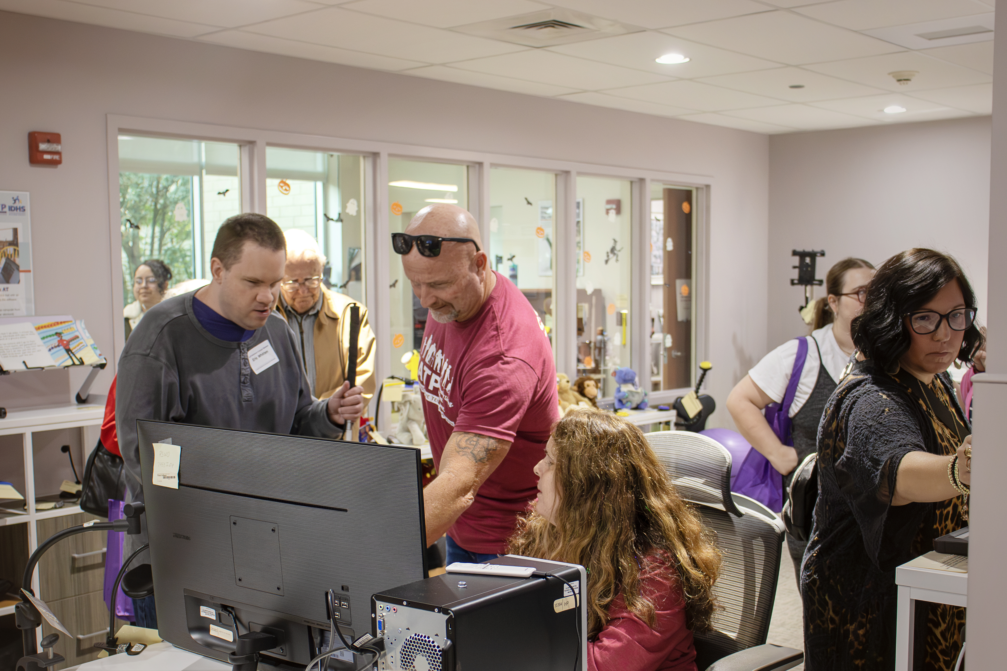 Several people gather around a desktop computer in the IATP Demo center